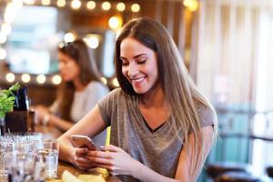 mujer feliz enviando mensajes de texto en el restaurante foto