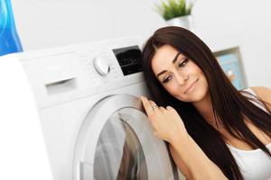 Portrait of young housewife with laundry next to washing machine photo