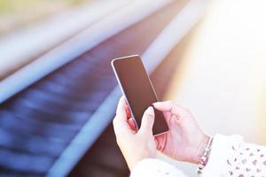 Hand holding smartphone with railway station background photo