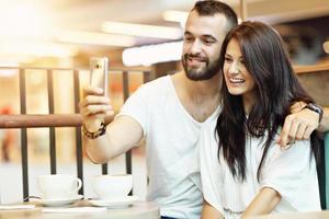 Romantic couple dating in cafe and using smartphone photo