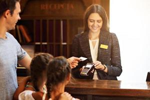 Happy family checking in hotel at reception desk photo