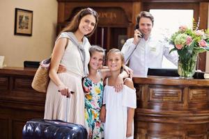 familia feliz registrándose en el hotel en el mostrador de recepción foto
