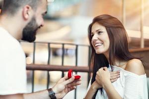 hombre guapo proponiéndole a una mujer hermosa en un café foto