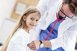 Little girl in clinic having a checkup with pediatrician photo