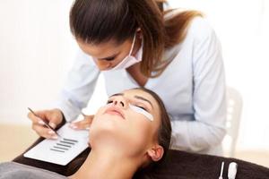 Adult woman having eyelash extension in professional beauty salon photo