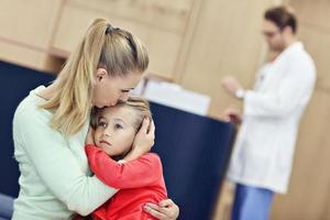 Little girl is crying while with her mother at a doctor on consultation photo