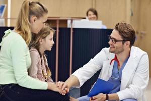 Doctor welcoming mother and daughter in clinic photo