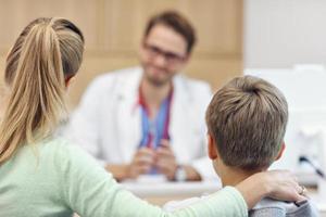 Little boy with mother in clinic having a checkup with pediatrician photo