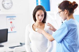 Adult woman being examined with stethoscope by female doctor photo