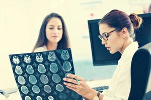 Adult woman discussing x-ray results during visit at female doctor's office photo