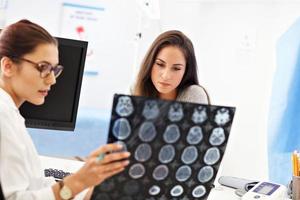 Adult woman discussing x-ray results during visit at female doctor's office photo