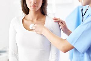 Adult woman being examined with stethoscope by female doctor photo