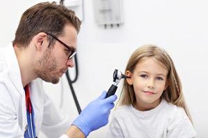 Close-up Of Male Doctor Examining Girl's Ear With An Otoscope photo