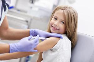 niña valiente que recibe inyección o vacuna con una sonrisa foto