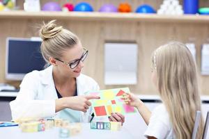 Child psychologist working with young girl in office photo