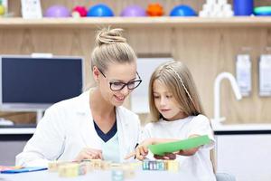 Child psychologist working with young girl in office photo