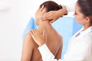 fisioterapeuta femenina ayudando a un paciente con problemas de espalda en la clínica foto