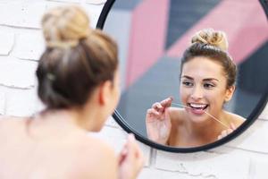 mujer joven cepillarse los dientes en el baño foto