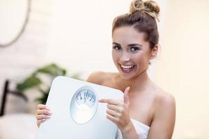 Happy woman holding bathroom scales in bathroom photo