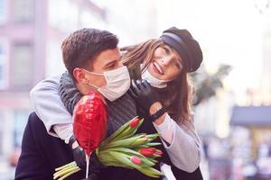 Happy couple celebrating Valentines Day in masks during covid-19 pandemic photo