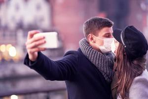 pareja feliz celebrando el día de san valentín con máscaras durante la pandemia de covid-19 foto