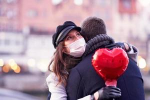 Happy couple celebrating Valentines Day in masks during covid-19 pandemic photo