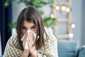 Brunette sneezing in a tissue in the living room photo