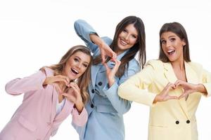 Three women in pastel suits posing over white background photo