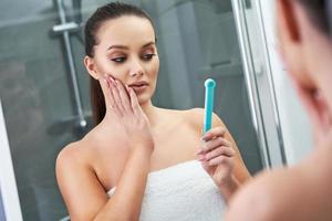 Woman looking on reflection in the mirror after shower photo