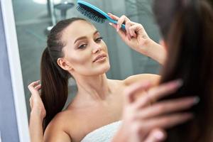 Woman brushing hair in bathroom after shower photo