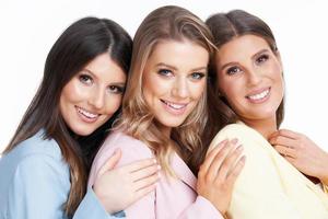 Three women in pastel suits posing over white background photo