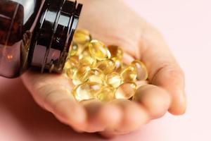 Vitamin D3 capsules poured out of the package. Care for health and immunity. A woman's hand. photo