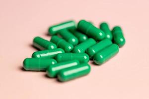 Green capsules on a pink background. photo