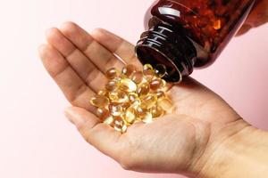 Vitamin D3 capsules poured out of the package. Care for health and immunity. A woman's hand. photo
