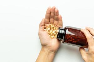 Golden capsules spilled on hands from the package. White background, space for text. photo