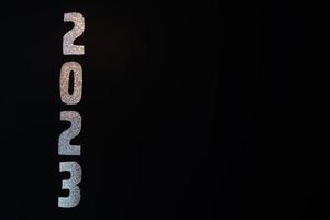 Happy New Year 2023. Golden numbers on a black background with glitter photo