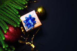 Christmas decorations with spheres gifts and pine needles with space for text and black background photo