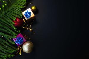 Christmas decorations with spheres gifts and pine needles with space for text and black background photo