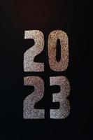 Happy New Year 2023. Golden numbers on a black background with glitter photo