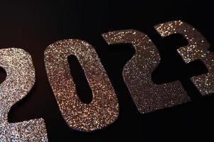 Happy New Year 2023. Golden numbers on a black background with glitter photo