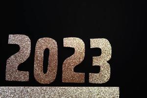 feliz año nuevo 2023. números dorados sobre un fondo negro con brillo foto