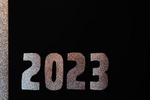 Happy New Year 2023. Golden numbers on a black background with glitter photo