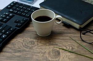 Wood office desk with a cup of coffee, a glasses, and a laptop. Concept photo about office desk.