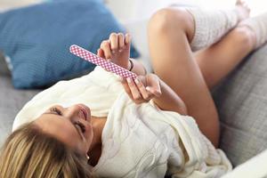 Happy woman filing nails on sofa photo