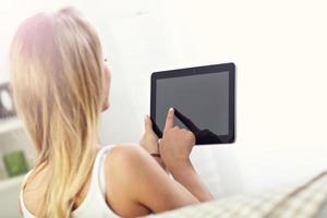 Happy woman with tablet on sofa photo