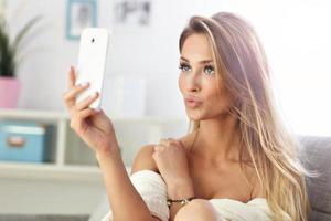 mujer feliz tomando selfie en el sofá foto