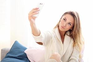 mujer feliz tomando selfie en la cama foto