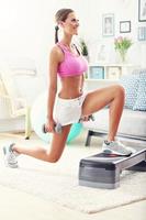 Sporty woman using step platform at home photo