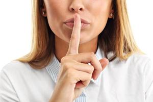 Adult woman holding a finger on her lips over white background photo