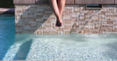4k looping naadloos cinemagraph van vrouw swinging voeten bovenstaand zwemmen zwembad water video